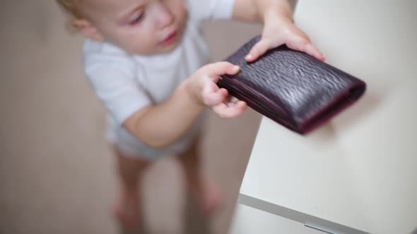 little girl takes a wallet from a shelf, carries it away and returns it to the shelf alt