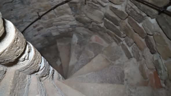 Descending the spiral staircase to the dungeon. Ancient stone staircase in the tower.