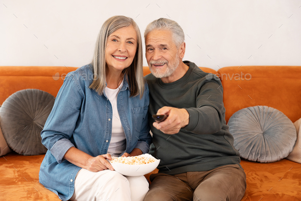 Elderly Couple Watching Tv Eating Popcorn At Home..