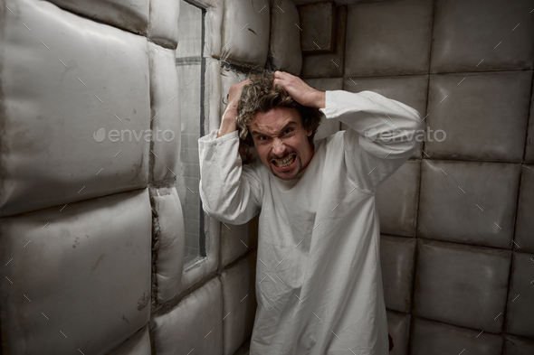 Calm man with schizophrenia mental disorder in white padded room