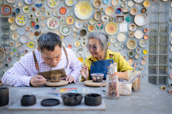Asian retired couple is engaged in pottery making and clay painting activities. - Stock Photo - Images