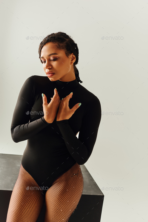 alluring african american woman in sexy tights and bodysuit posing next to  black cube, fashion Stock Photo by LightFieldStudios