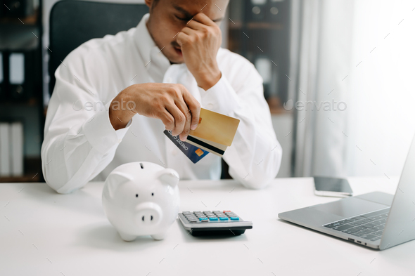 Financial owe, Asian man sitting, holding credit card, stressed