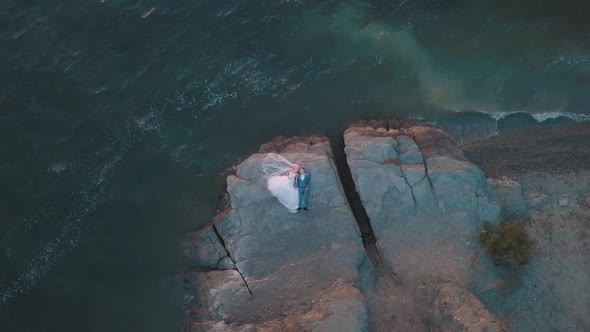 Groom and Bride Lying on a Mountainside By the Sea. Wedding Day. Aerial Shot alt