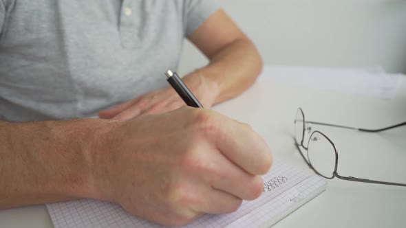 man drawing on a desk to his notepad alt