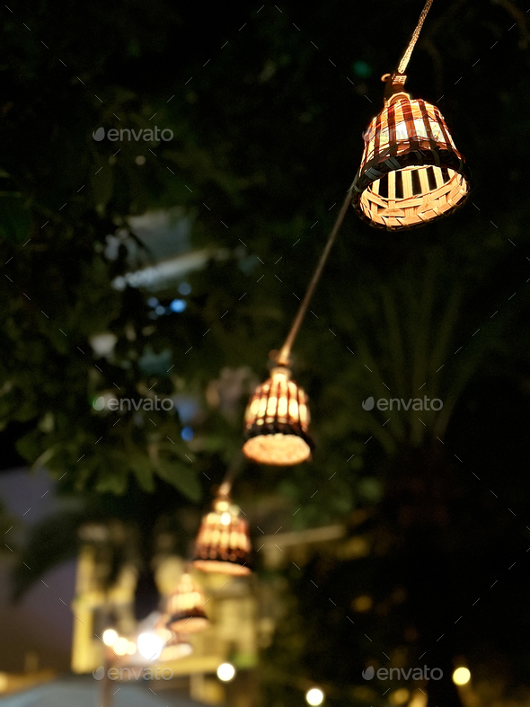 Stylish Outdoor Electric Lamps With Yellow Warm Light Surrounded By Green Tropical Palm Tree Leaves