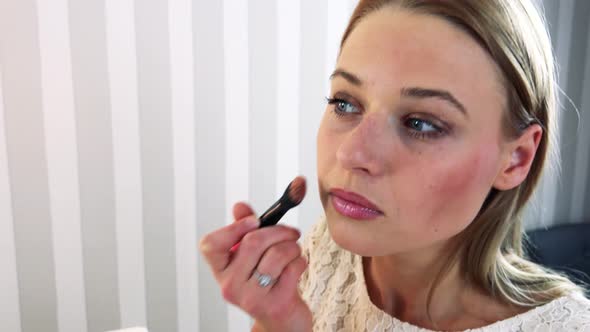 A Young Attractive Woman Makes Herself Up in Front of a Mirror alt