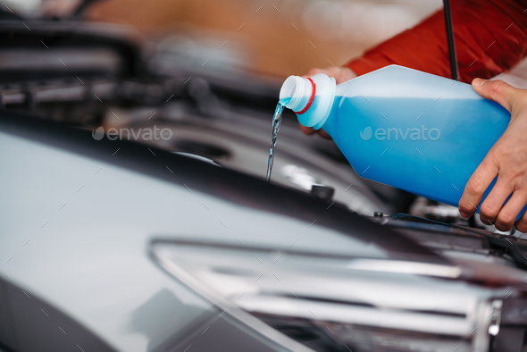 Pouring winter washer fluid into car reservoir during winter, protecting it  from freezing. Stock Photo by halfpoint