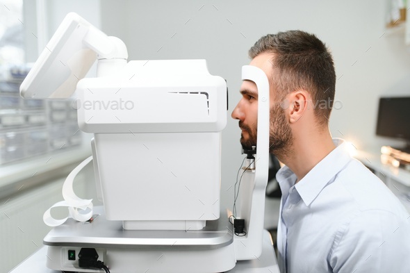 Handsome young man is checking the eye vision in modern ophthalmology clinic.