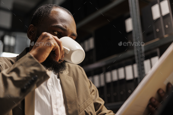 Private investigator drinking coffee while examining police documentation