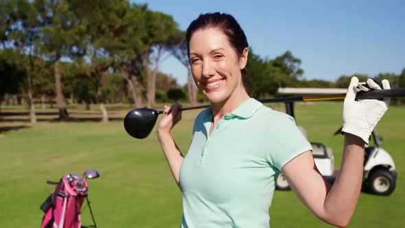 Golfer carrying golf club over shoulder while standing on the golf course alt