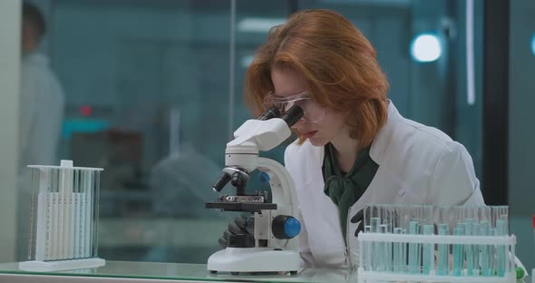 Medical Research of Sample of DNK or Blood in Crime Lab, Female Expert Is Looking in Microscope and alt