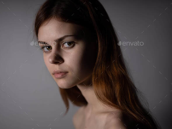 Red-haired woman naked shoulders side view dark background portrait ...