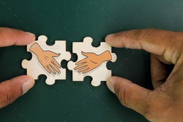 wooden puzzle with two shaking hands icons. the concept of deal or agreement.