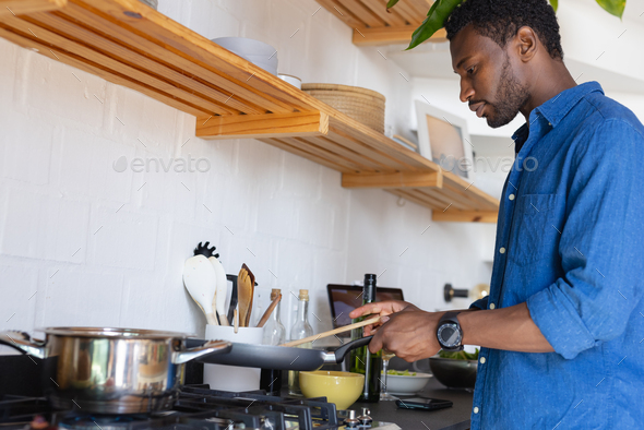 Happy African American Man Standing In Kitchen And Cooking Dinner Stock