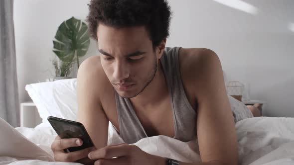 Man Lying in Bed and Using Gadgets alt