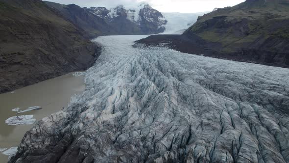 Large glacier flowing down narrow mountain valley in Iceland. Tracking shot. alt