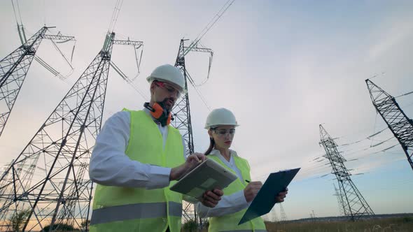 Professional Electricians Work Together Near Transmission Lines, Stock 