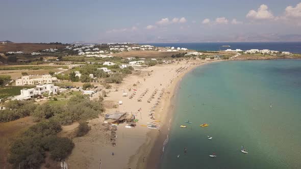 Rising drone shot of tourists enjoying the golden sands of a public beach on the greek island of Par alt