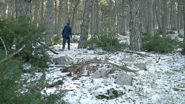 Young Man Walking on Snow in Mountain Forest