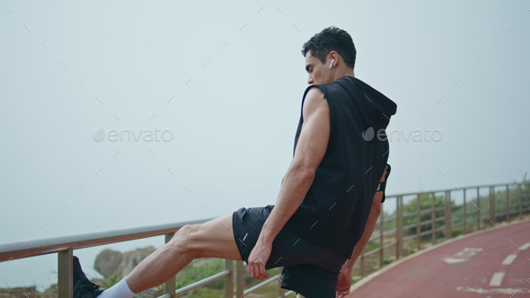 Fitness Exercise. Athletic Active Man With Fit Muscular Body Stretching,  Exercising Before Running. Athlete Warming Up And Preparing For Workout.  Male Runner Doing Stretches Outdoor. Sports Concept Stock Photo