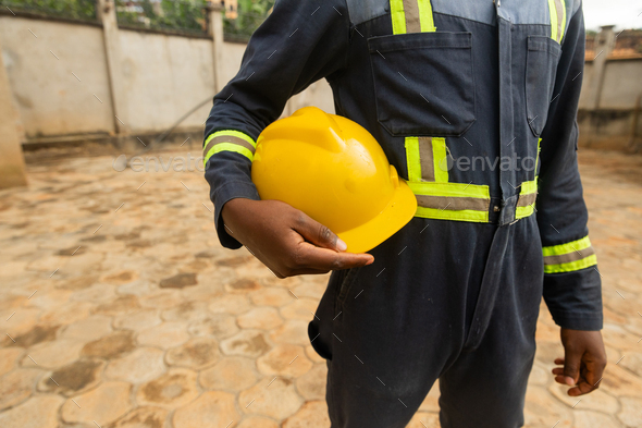Faceless close-up of a technician dressed in his work outfit holding his yellow helmet