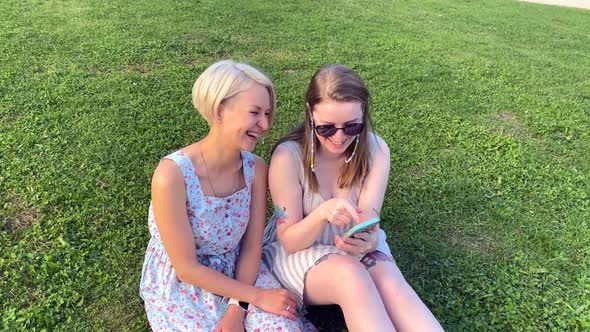 Two Girls Look at a Smartphone and Laugh