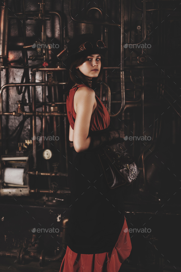 Stylish teen girl model in steampunk image in brown retro dress and top hat posing