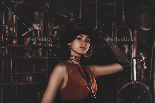 Classy teen girl model in steampunk image in retro brown dress and top hat