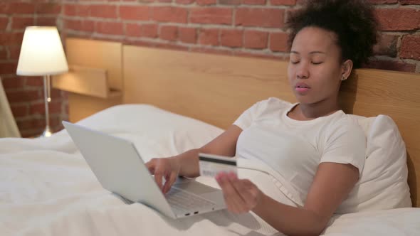 African Woman with Unsuccessful Online Payment on Laptop in Bed alt