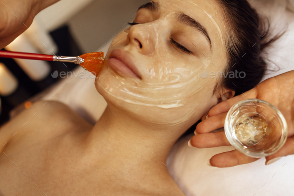 Beauty master applies a rejuvenating mask to the clients face