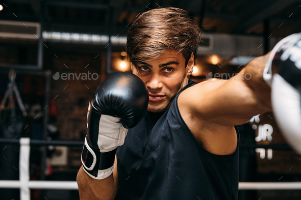 Close up of a male sportsman doing shadow boxing inside a boxing ring ...