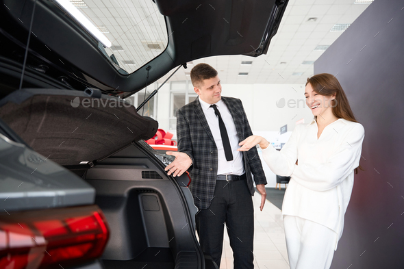 Woman choosing automobile talking with dealership agent about model advantages