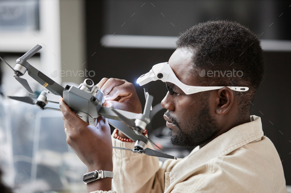 Black Man Assembling Drone and Flashlight in Tech Repair Shop