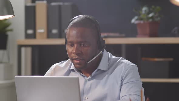 Afro-American Call Center Worker Speaking on Web Call on Laptop alt