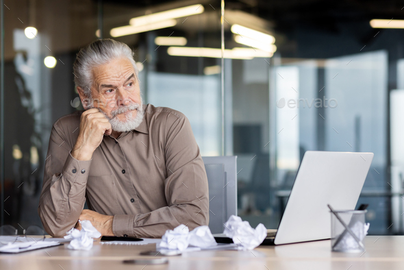 Upset frustrated gray haired boss sitting inside office at workplace, mature man old businessman in