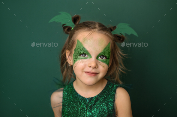 Portrait of cute pretty girl with painted dragon wings on face