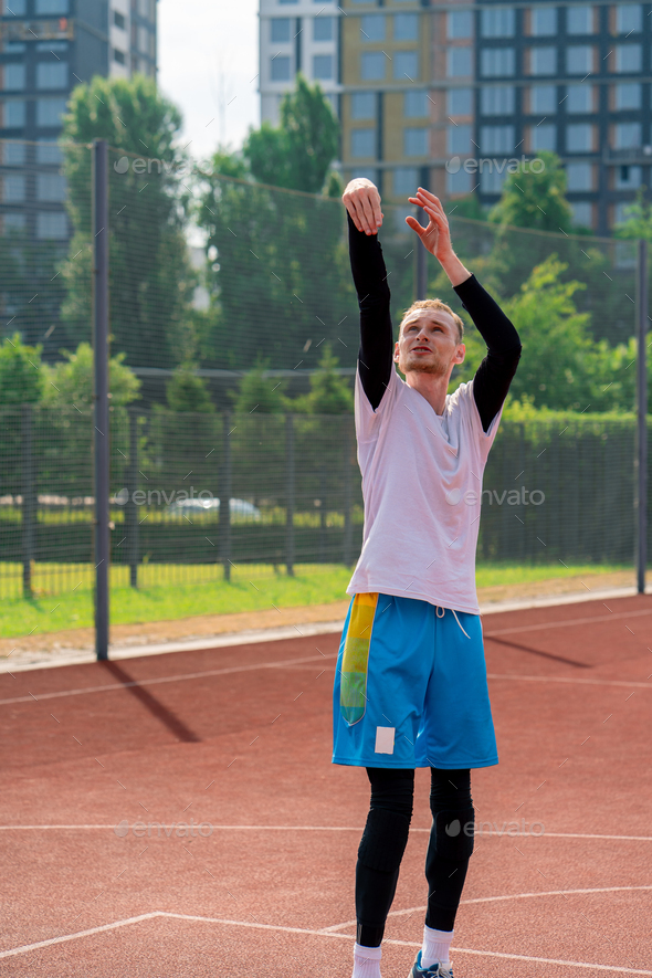 tall guy basketball player throws a ball into a basketball hoop at a