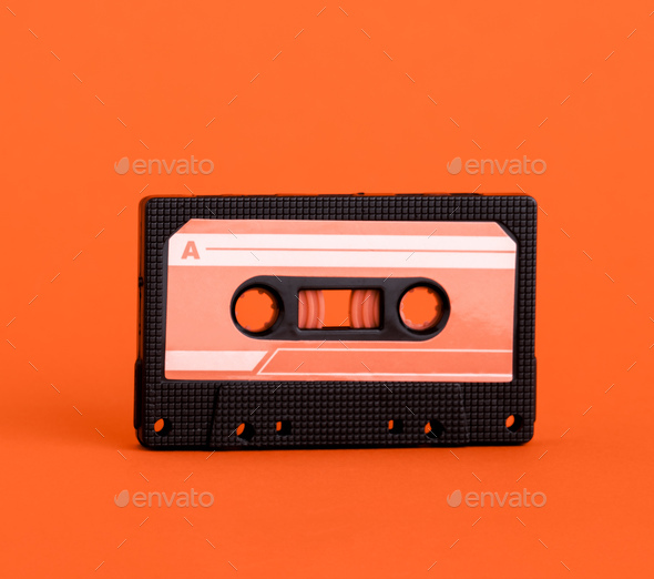 Black audio cassette with orange label on orange background. Minimal art music poster.