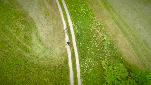 Aerial view of man and woman cycling on dirt road in the summertime. alt