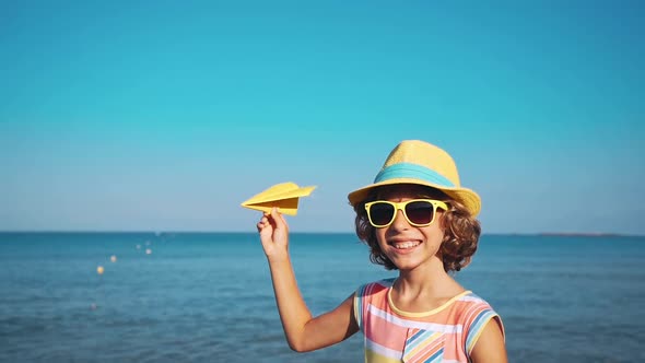 Happy Child Playing with Toy Airplane against Sea and Sky Background alt