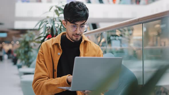 Young Indian Man Looking at Laptop Screen Checking Email Smiling Enjoying Free Time Browsing Web alt