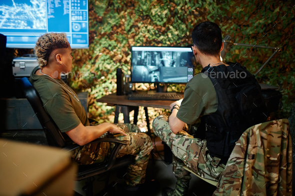 Two young intercultural male and female officers looking at computer screen