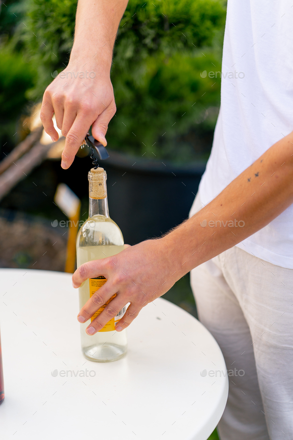 Closeup shot of a male sommelier's hand using a corkscrew to unscrew