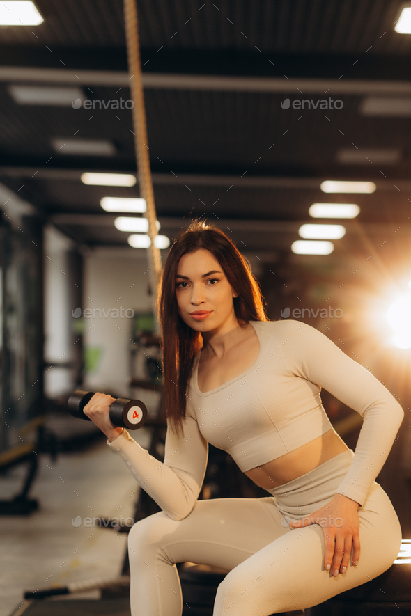 Strong woman pumping iron in a gym with the help of three-kilo