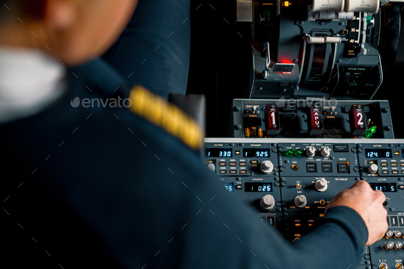 The captain presses the buttons on the control panel to start the engine of the plane flight