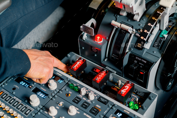 The captain presses the buttons on control panel to start the engine of the plane flight