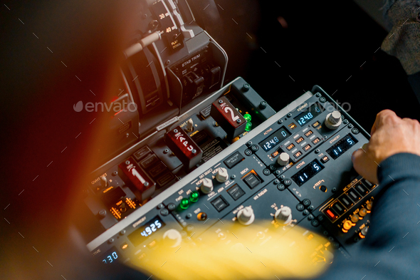 The captain presses the buttons on the control panel to start the engine of the plane flight