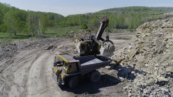 Excavator Loads Stones into a Dump Truck