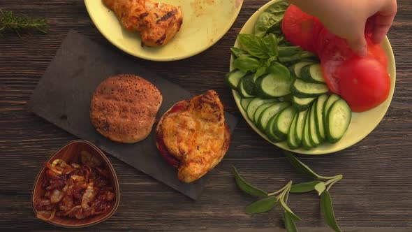 Top View of the Hands Putting a Grilled Chicken Fillet on the Bun of the Burger alt